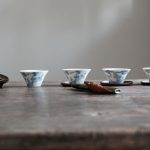 Chinese Tea Set - a wooden table topped with cups and saucers