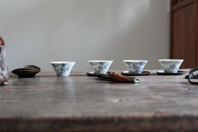 Chinese Tea Set - a wooden table topped with cups and saucers