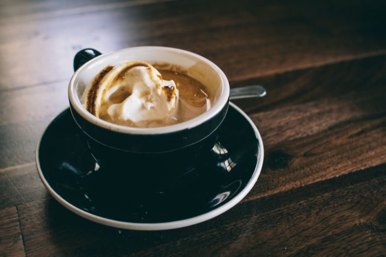 Gongdao Bei Cup - white and black ceramic mug filled with brown latte on round black ceramic saucer