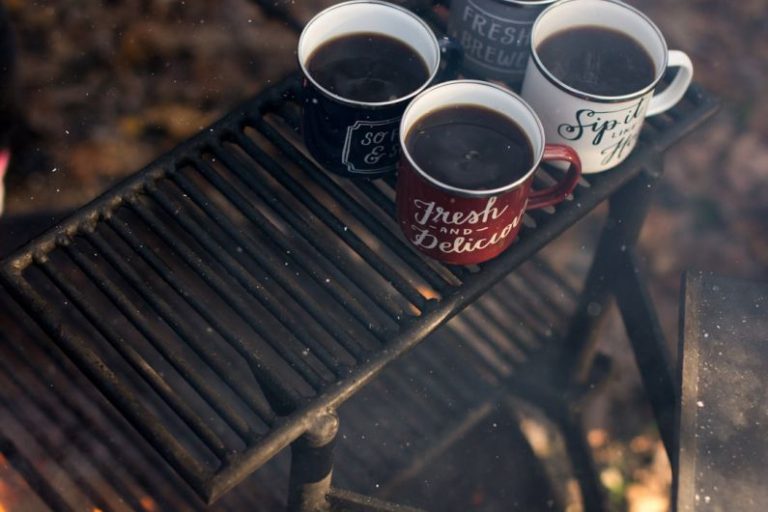 Black Tea Brewing - four assorted-color ceramic mugs on black grill frame
