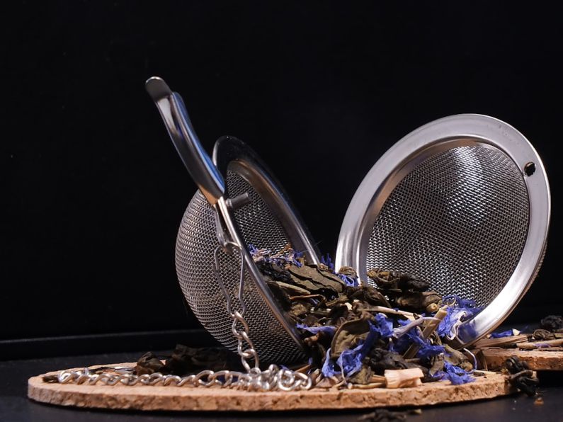 Tea Infuser Ball - stainless steel spoon and fork on brown wooden tray