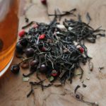 Tea Steeping Glass - red and black round fruit on brown wooden table