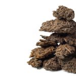 Pu-Erh Tea Cake - brown dried leaves on white background