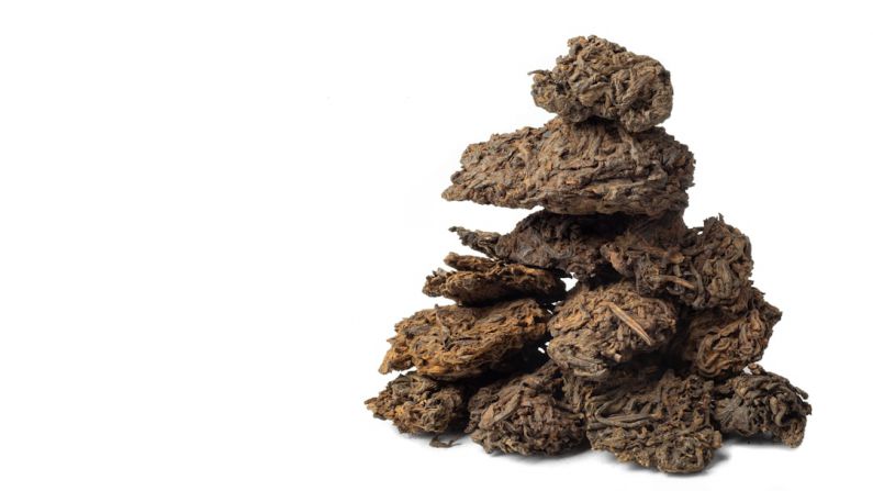Pu-Erh Tea Cake - brown dried leaves on white background