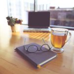 Moroccan Mint Tea - clear eyeglasses on top of black book beside clear glass mug