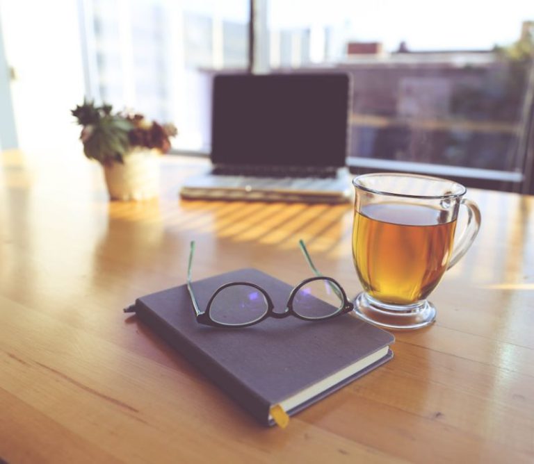 Moroccan Mint Tea - clear eyeglasses on top of black book beside clear glass mug
