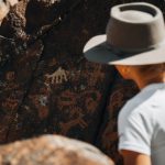 Tea History Scroll - a man wearing a hat standing next to a rock