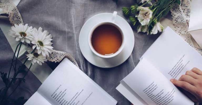 Japanese Tea Poetry - White Ceramic Teacup With Saucer Near Two Books Above Gray Floral Textile