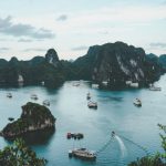 Vietnam Tea Farming - high-angle photography of boats on water near hill during daytime